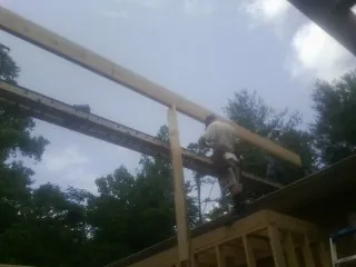 Carpenter setting a ridge beam over a new addition frame — Ice Dam Removal by Roofing Brothers in Crane