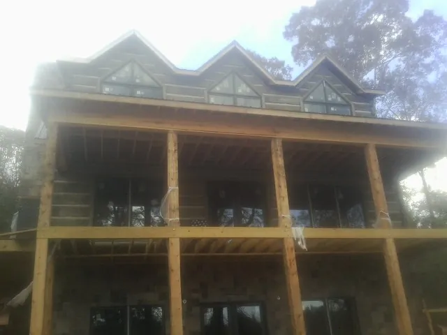Dormers and porch framing on a large log home under construction — Roof Coating work by our crew in Crane