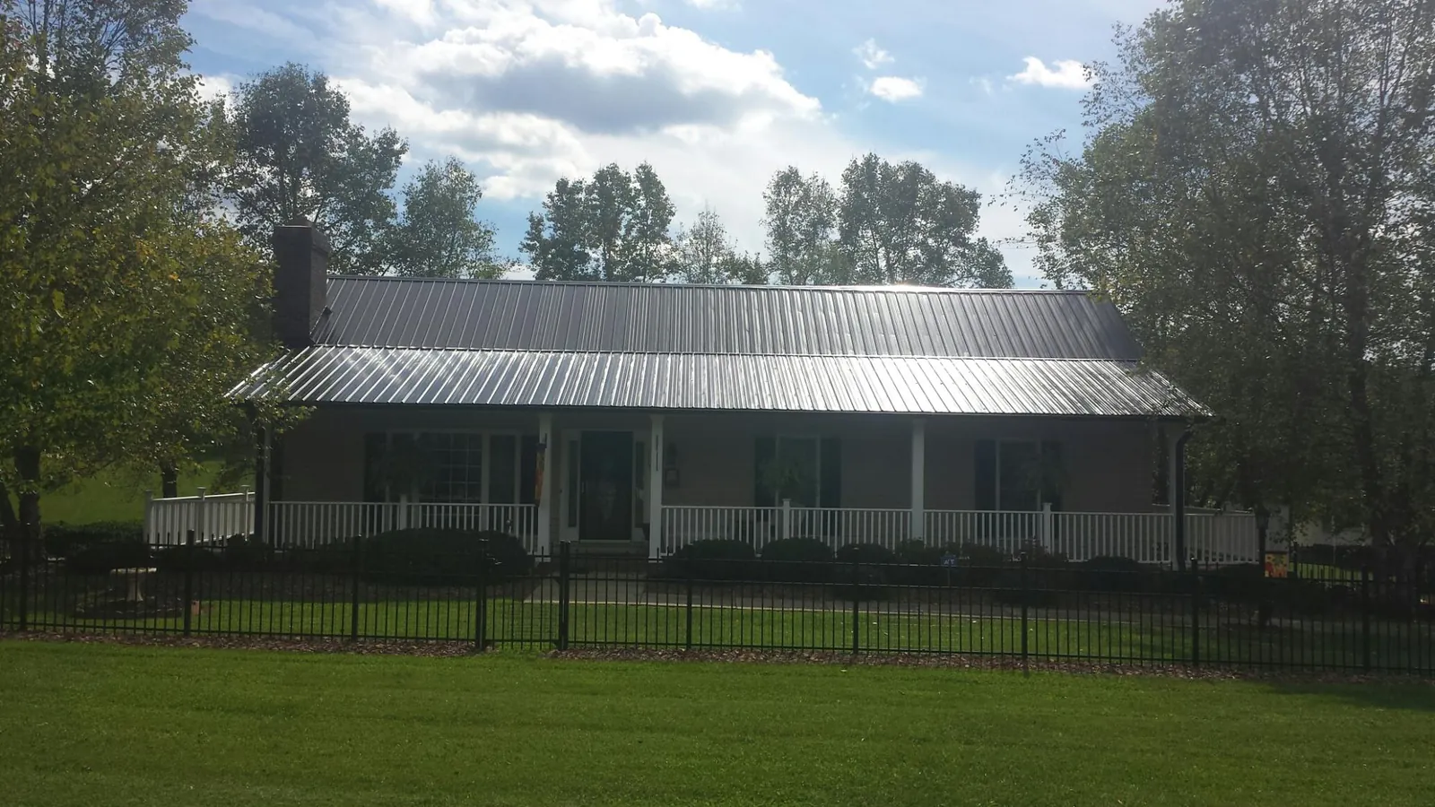 Gray metal roof on a brick ranch with a full width front porch — Gutter Guard Installation work by our crew in Crane